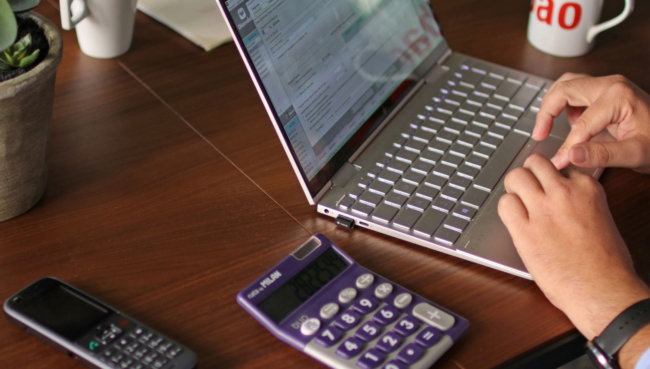 Una persona trabajando con un ordenador, calculadora y teléfono en las oficinas de Estudio Asesores en Bilbao